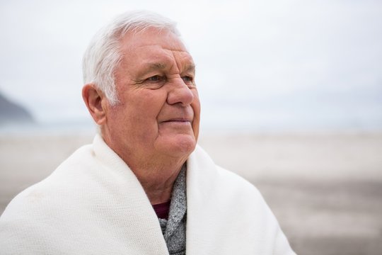 Senior Man Wrapped In Shawl On Beach