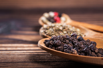Spices close up in a spoon on a wooden table