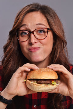 Graciosa y expresiva mujer nerd comiendo hamburguesa.