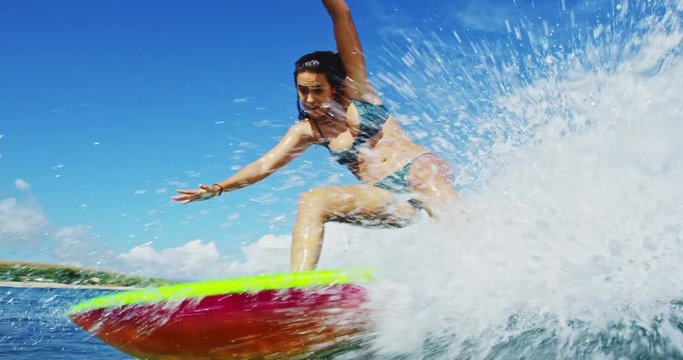 Surfer girl riding wave sprays water splashes camera. Shot on RED.
