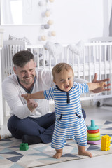 Obraz premium Dad supporting baby making first steps