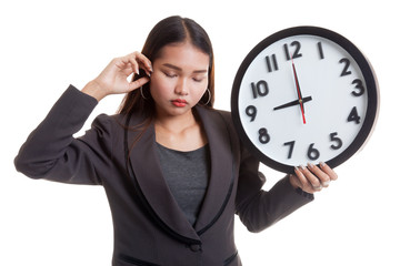 Sleepy young Asian business woman with a clock in the morning.