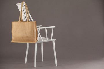 Beige fabric bag hanging on a white chair