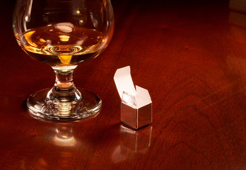 Do good things come in the smallest packages? Tiny gift box on wooden table with brandy snifter