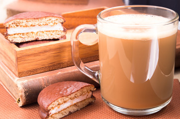 Glass mug with hot chocolate and biscuits in a wooden tray