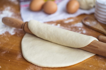 Dough, eggs and rolling pin on the kitchen table for cooking