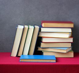 Stack of books on the table with a red tablecloth.