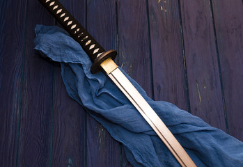 Naklejka premium miecz katana japonia na tle drewna z niebieskim szalem