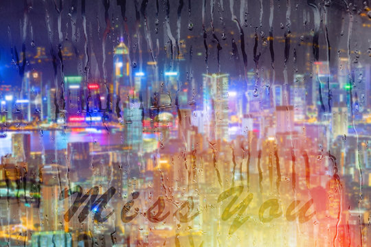 Rainy season with cityscape background, the inscription on the glass,miss you word on window.