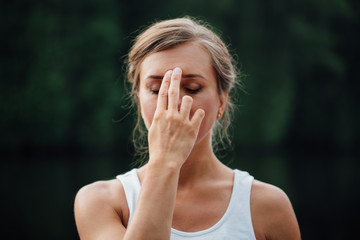 Young Woman Doing Yoga Meditation Exercises, symbolic hand gestures mudra. on the background of forest and river