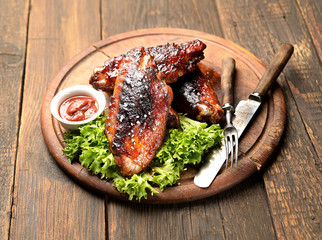 grilled turkey wings with lettuce on a wooden background
