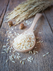 Closeup Jasmine rice in wooden spoon on wooden table background.