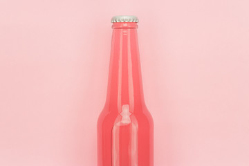 glass bottle of pinkish soda drink on pink background