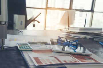 business working woman using smart phone and tablet while working with laptop and reading report , graphs , charts, document at work.