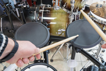 Fototapeta na wymiar Hands drummer drumsticks knock on the black electric drum, close-up in the first person