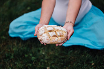 pregnant yoga prenatal maternity with freshly baked homemade bread in hands in park on the grass.
