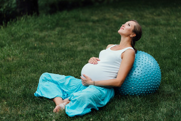 pregnant yoga prenatal doing different exercises with fitball. in park on the grass, breathing, stretching, Pilates.