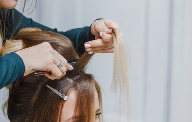 Fototapeta premium hands of woman combing hair and doing bouffant her client in beauty salon