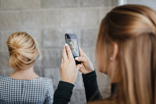 Woman hairdresser taking picture on smartphone of her client hairstyle