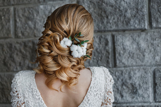 Rear view close-up of the finished wedding hairstyles in the form of winter bride with cotton flowers decoration