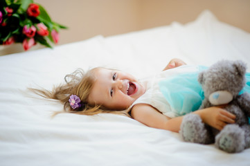 Obraz na płótnie Canvas The charming little girl lies on a big bed.