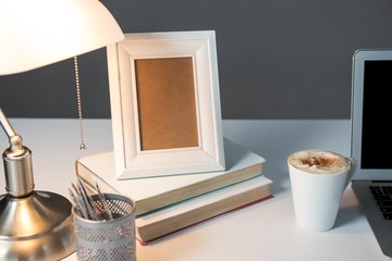 Picture frame, cup of coffee with books and table lamp