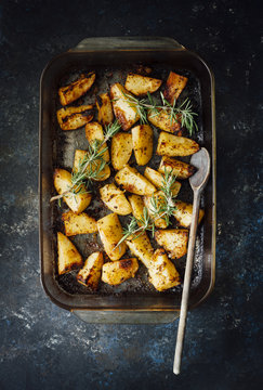 Overhead view of roasted potatoes in a pan garnished with rosemary