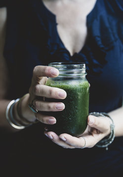 Female hands holding green smoothie