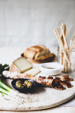Sausage and cheese on a wooden board with loaf of bread