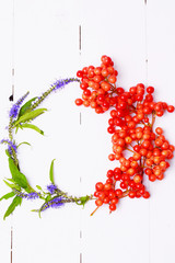 Autumn wreath arrangement of berries and flowers on white wooden background view from above