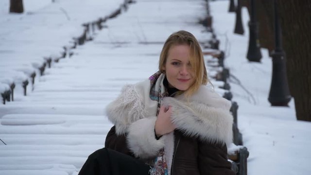 Beautiful young model on a photo shoot in the winter in a snow blizzard. Very cold.