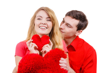 Couple holds red heart shaped pillows love symbol