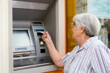 Fototapeta na wymiar elderly woman inserting credit card to ATM