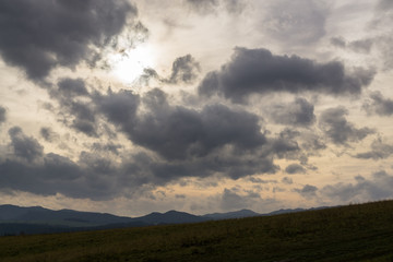 Fototapeta premium Clouds and sunrays over the meadow. Slovakia