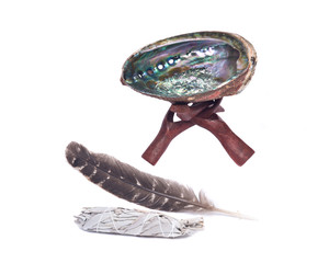Sage smudge stick, bright polished rainbow abalone shell and grade A barred turkey smudging feather with wooden cobra stand isolated on white background