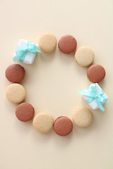 Macaroons with small gifts on ivory background,top view 