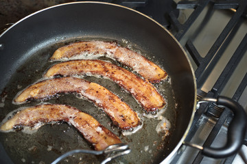 Bacon frying in a large pan