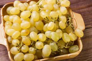 Group of tasty fresh green grapes close up in a bowl on wooden background