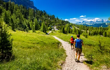 Fotobehang Pair of excursionist walking on mountainous trail. Summer Trekking © meskolo