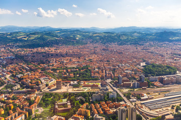 Aerial view of Bologna city in Italy with Asinelli Towers, San Luca Basilica church on Bologna hill and train station.