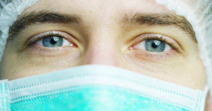 close up portrait of a surgeon or doctor with mask and headset ready for operation in hospital or clinic. The surgeon smiles safe and proud of himself. Concept of medicine, hospitals and doctors, care