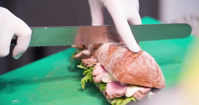 Sandwich cooking serving 4k video: chef cuts sandwich with knife. Food preparing in restaurant