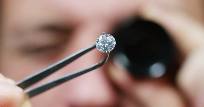A goldsmith in jewelry checks the quality of luxury brilliant diamonds. The diamonds of high caliber shine the light and pure. Concept: Jewelry, luxury, glitz, gloss and goldsmith.