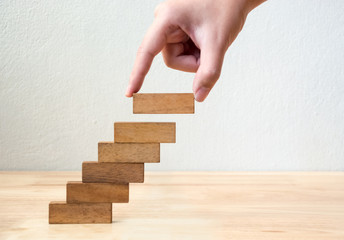 Hand arranging wood block stacking as step stair. Business concept for growth success process