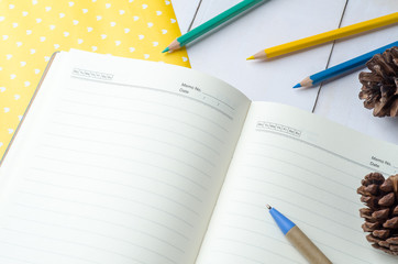 Blank daily planner notebook with pen and color pencils on white