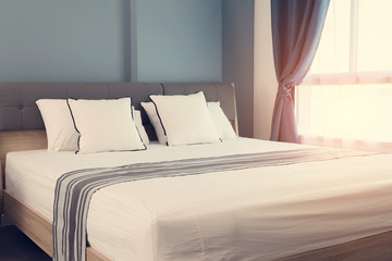 Bed maid-up with clean white pillows and bed sheets in beauty room. Close-up. Lens flair in...