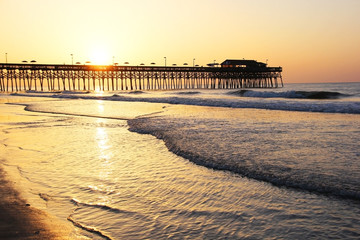 Golden sunrise over Atlantic ocean.  Atlantic Ocean view with a pier in Myrtle Beach area, South Carolina, USA.