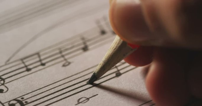 A musician or composer composes a song or a musical work, writing notes in pencil on the pentagram. The composer, first hears the sound of the note then writes and so on is composed the music. Concept