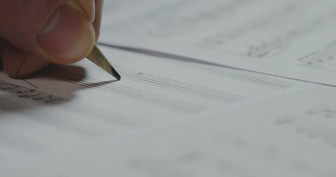 A musician or composer composes a song or a musical work, writing notes in pencil on the pentagram. The composer, first hears the sound of the note then writes and so on is composed the music. Concept