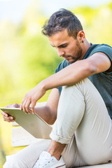 handsome man outdoors with a tablet